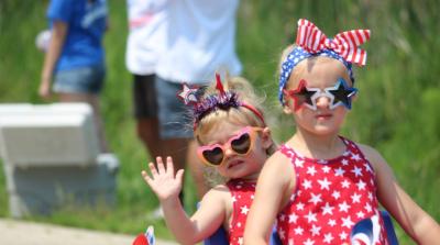 Two small girls dressed in red and blue stars and stripes outfits and sunglasses