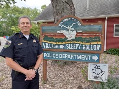 Chief Samuel J. Parma Jr. standing outside in front of Sleepy Hollow Village welcome sign