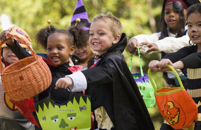 Group of multiethnic children in costume holding bags for trick or treating