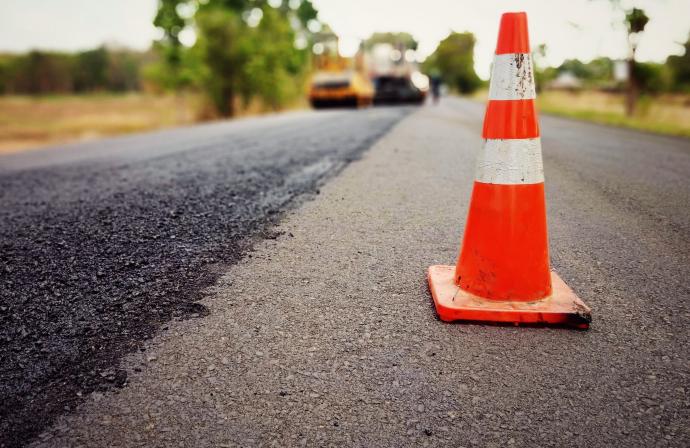 Orange traffic cone on a blacktop road under cnstruction
