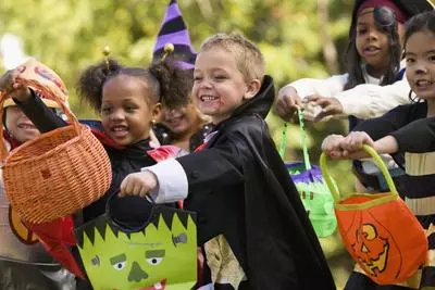 Group of multiethnic children in costume holding bags for trick or treating